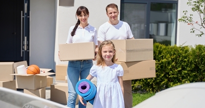 Couple with daughter carrying moving boxes