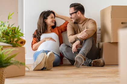 Pregnant wife with partner sitting on floor in new home