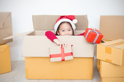 Portrait of girl wearing santa hat sitting in moving box