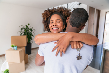 Woman hugging partner holding keys to new home